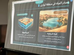 Infographic in Arabic titled 'مصادر المياه في منطقة أوباري' comparing freshwater and saltwater sources, with illustrations of desert terrain and a blue oasis/lake scene and brief descriptions under each image.