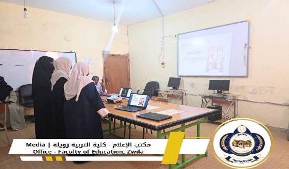 Women in hijabs use laptops around a table during a training session in a classroom, with a projector screen, whiteboard, and a faculty banner visible.