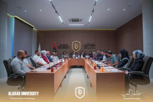 A formal meeting in a modern conference room at Al Arab University, with attendees seated around a U-shaped wooden table and university logos on the wall.