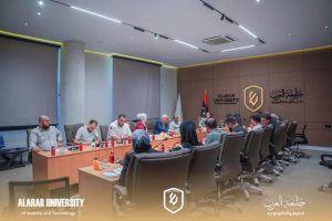 A diverse group of people sits around a long conference table in a modern meeting room at Al-Arab University, with flags and a university logo on the wall.