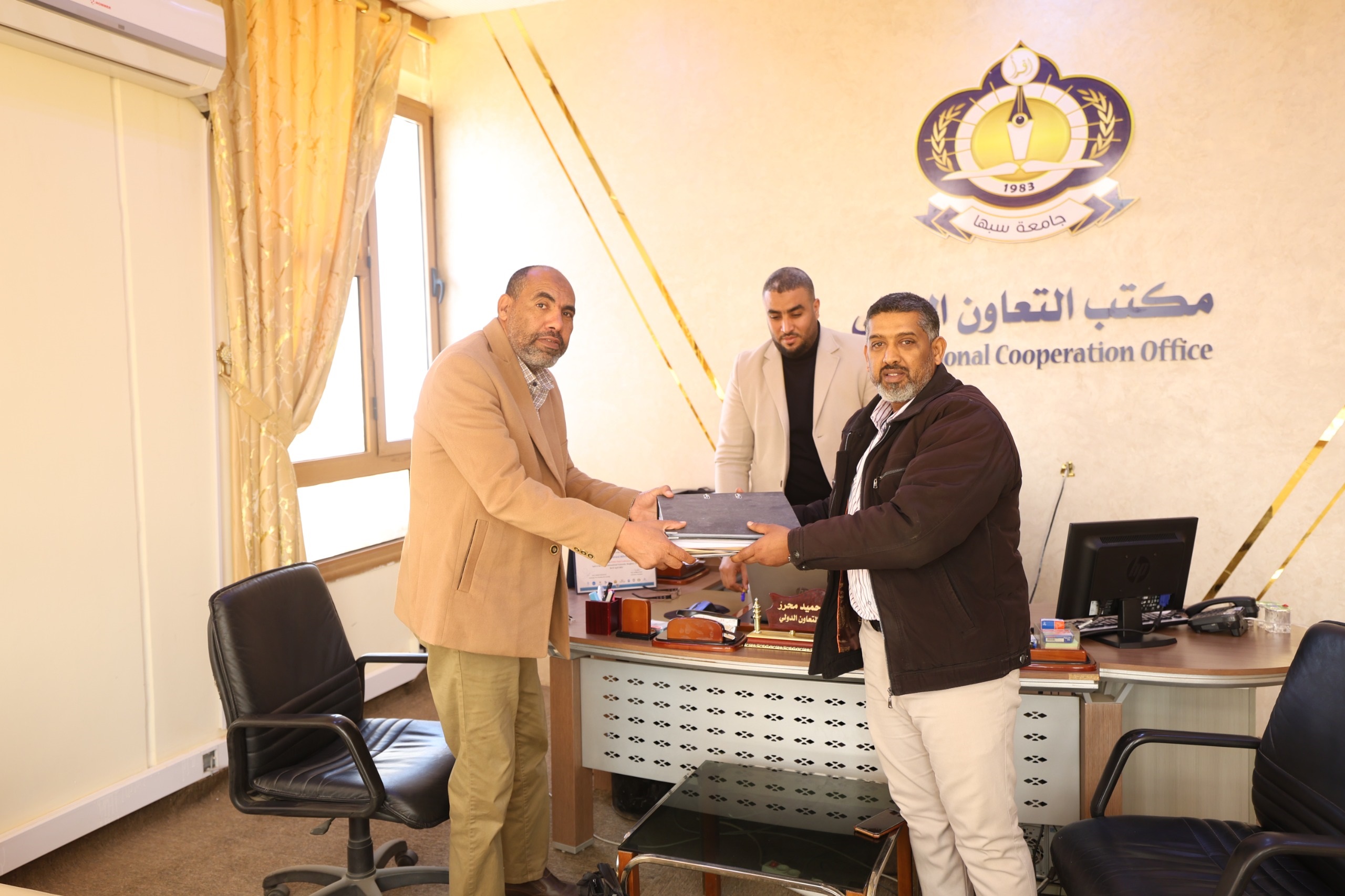 مكتب التعاون الدولي بالجامعة يتسلم ويسلم ملف مشروع “صحة SAHA” بجامعة سبها لاعتماده بكلية التجارة والعلوم السياسية