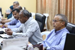 32577579-F4C5-40F2-91CB-67893049C75E - جامعة سبها | Sebha University Group of men in a conference room seated at a table reviewing documents