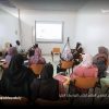 Group of adults seated in a small classroom watching a projected presentation.