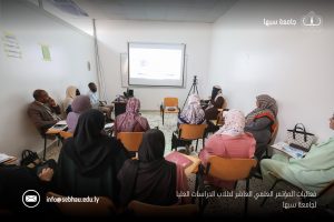 3A78A6EF-CB6A-46F0-BDB6-CC5202221E1A - جامعة سبها | Sebha University Group of adults seated in a small classroom watching a projected presentation.