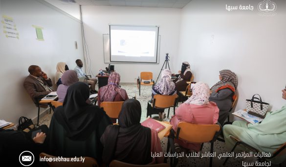 3A78A6EF-CB6A-46F0-BDB6-CC5202221E1A - جامعة سبها | Sebha University Group of adults seated in a small classroom watching a projected presentation.