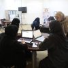 Women in hijabs seated around a table with laptops in a classroom or conference room, collaborating on a project.