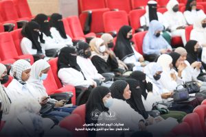 IMG_8392.jpg - جامعة سبها | Sebha University Women wearing hijabs seated in red auditorium chairs at a conference, many wearing masks.