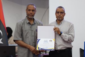 Two men pose together, one holding a framed certificate during a formal presentation or ceremony.