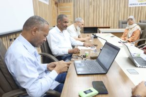 5984A02A-E3BD-4493-ABEE-0218796E8A0D - جامعة سبها | Sebha University Group of professionals in a conference room, some using laptops and taking notes during a meeting.