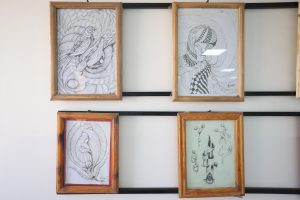 WhatsApp Image 2026-06-14 at 12.43.22 PM (2) - جامعة سبها | Sebha University Two large wooden-framed black-and-white abstract drawings with swirling patterns hung on a light wall in a gallery setting.