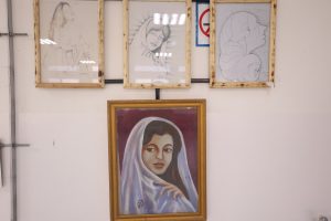 WhatsApp Image 2026-06-14 at 12.43.22 PM - جامعة سبها | Sebha University Row of framed drawings on a wall, featuring light pencil portraits of women and an abstract line-art figure in wooden frames.
