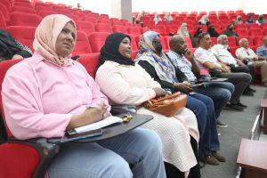 WhatsApp Image 2026-06-14 at 12.43.23 PM - جامعة سبها | Sebha University Audience seated in a red theater with several women wearing hijabs watching a presentation.