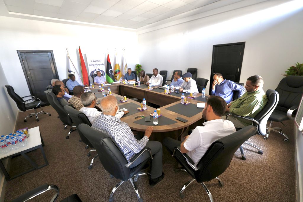 Group of professionals seated around a large conference table in a bright meeting room, with flags in the background behind the attendees.