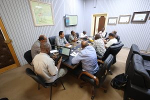 362C60B7-04E5-4A9E-9172-14770945D9DE - جامعة سبها | Sebha University Group of men seated around a long conference table in a meeting room, some with laptops and notepads.