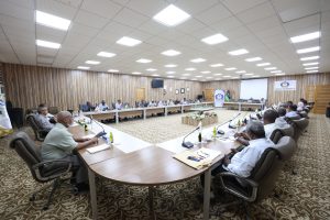 889B4BFC-277C-4887-A847-A8174294C7A4 - جامعة سبها | Sebha University Large conference room with a U-shaped table setup and 20+ attendees discussing, flags and a SEIBA University banner in the background.