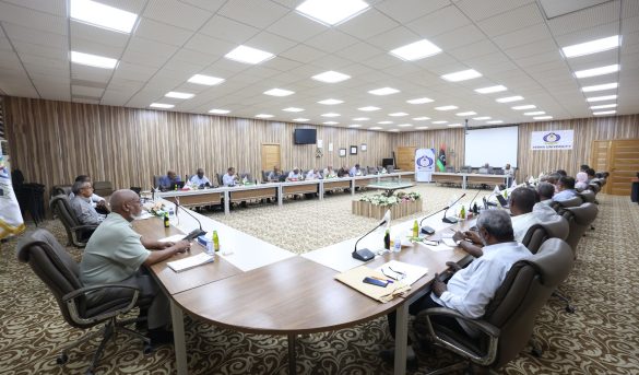 Large conference room with a U-shaped table setup and 20+ attendees discussing, flags and a SEIBA University banner in the background.
