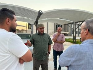 WhatsApp Image 2026-07-09 at 10.21.20 AM - جامعة سبها | Sebha University Group of men standing outdoors in conversation, man in green shirt gesturing as he speaks.