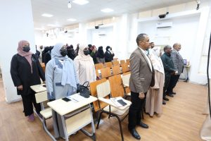 082C4F6C-1219-483B-8578-AD93BF470361 - جامعة سبها | Sebha University Group of men and women wearing masks standing in a classroom, facing forward during a ceremony or event.