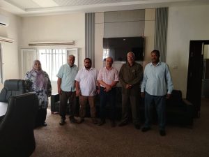 Seven people stand side by side in a meeting room, posing for a group photo.