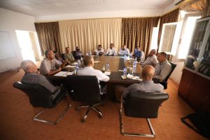 7B781DDD-F971-456A-B8AB-DA6F21923FDF - جامعة سبها | Sebha University Approximately fourteen professionals seated around a rectangular conference table in a meeting room, engaged in discussion.