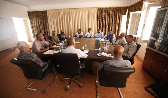 Approximately fourteen professionals seated around a rectangular conference table in a meeting room, engaged in discussion.