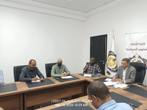 7F198B72-EE09-4E05-9A9E-455CD04BC8B6 - جامعة سبها | Sebha University Group of men seated around a conference table signing papers, with a banner and flag in the background.
