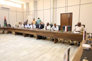 inbound1939632501219903898 - جامعة سبها | Sebha University Formal meeting in a conference room with officials seated along a long table and national flags on the table.",