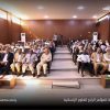 Audience seated in a university conference hall for the fourth humanitarian sciences conference, logo and Arabic title visible at top and bottom