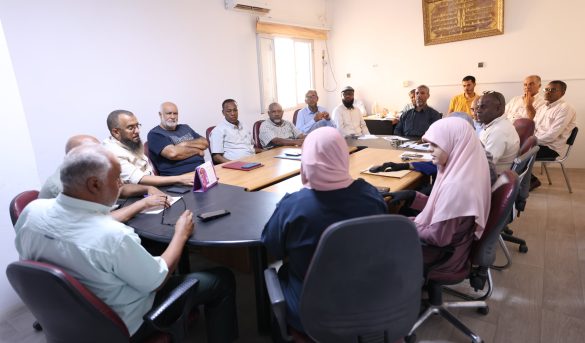 inbound3766009776805406054 - جامعة سبها | Sebha University Group of adults seated around a conference table in a meeting room, discussing and taking notes.