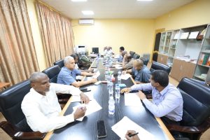 Group of professionals seated around a long conference table, taking notes during a meeting.