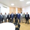 Group of professionally dressed men standing in a conference room, posing for a group photo.
