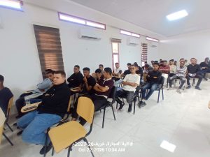 IMG-20261024-WA0004 - جامعة سبها | Sebha University A classroom with many students seated in rows, listening to a lecture in a bright, modern room with white walls and air conditioners on the wall.