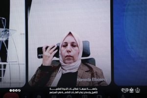 IMG-20261029-WA0027 - جامعة سبها | Sebha University Woman wearing hijab on a video call raises her hand in a virtual meeting.